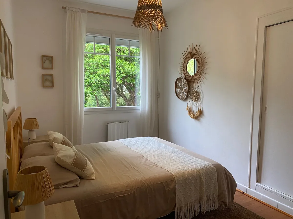 Chambre ouverte sur les pins, miroir soleil et jeté de lit en lin
