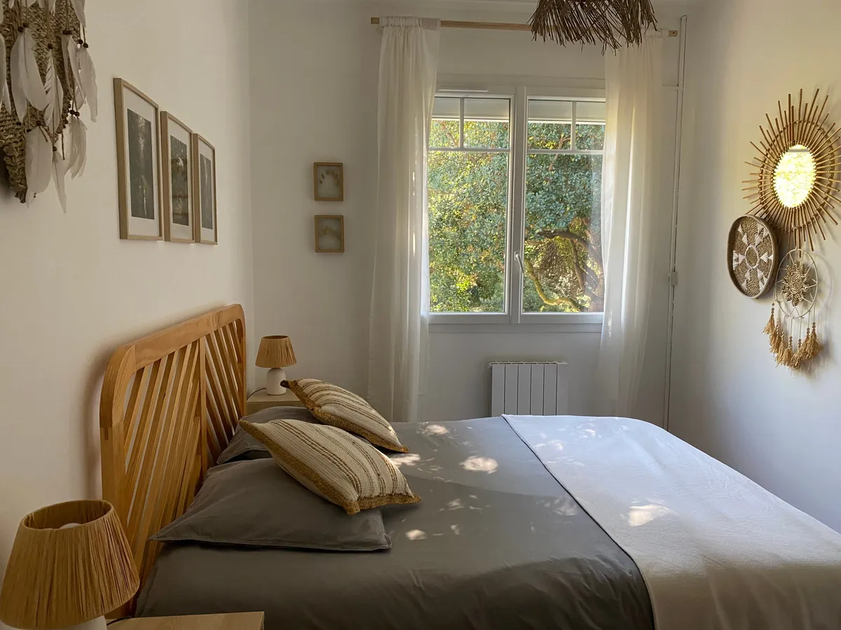 Chambre au linge gris et blanc, tête de lit en rotin et miroirs en fibres naturelles