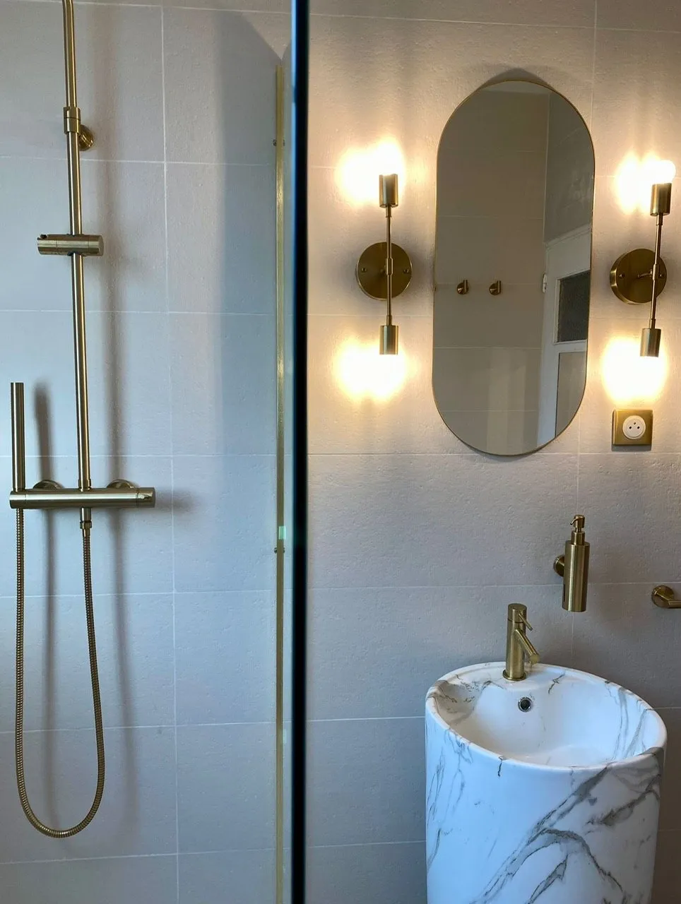 Douche vitrée à la robinetterie en laiton, à côté de la vasque colonne