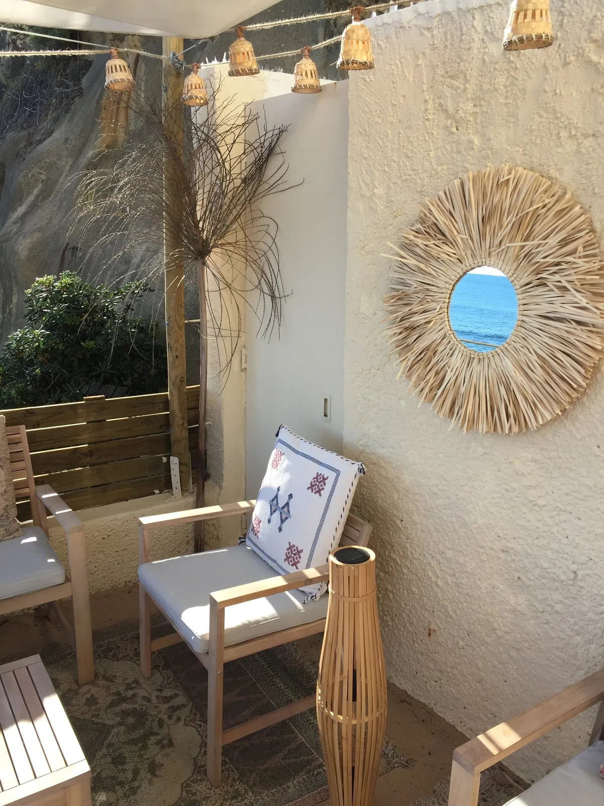 Fauteuil en bois sous un grand miroir soleil, lumière de fin de journée