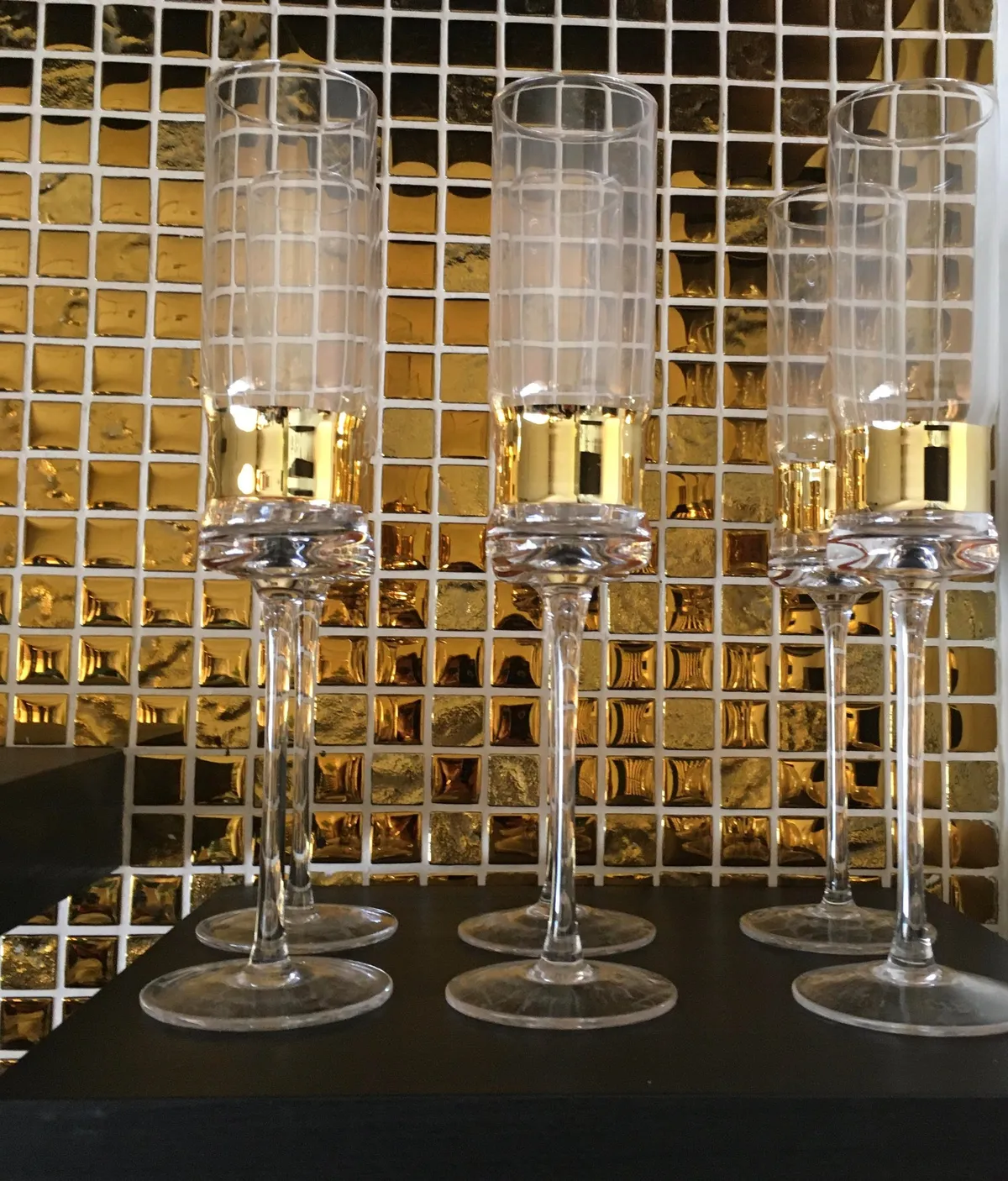 Flûtes à champagne alignées devant la mosaïque dorée du bar