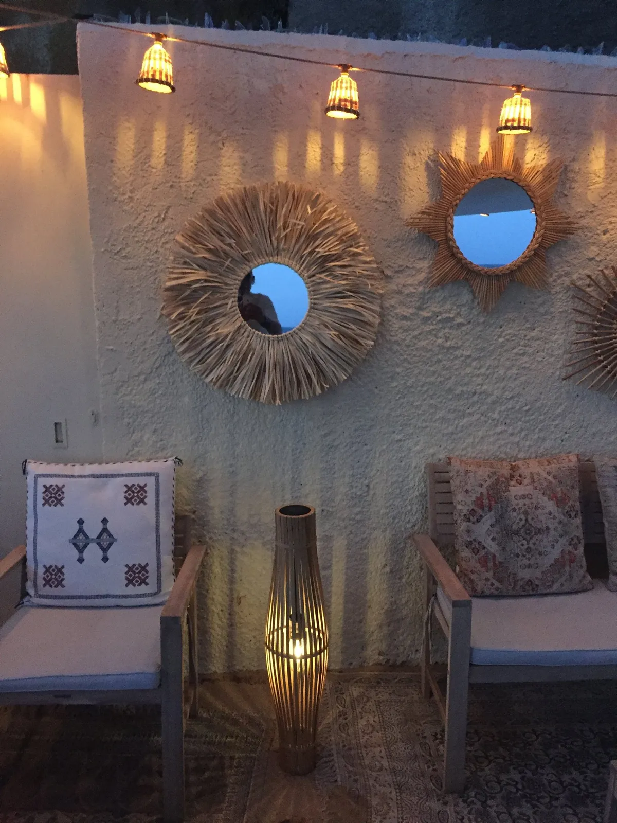 Miroir soleil en fibres naturelles, lanternes tressées et fauteuils au coussin brodé