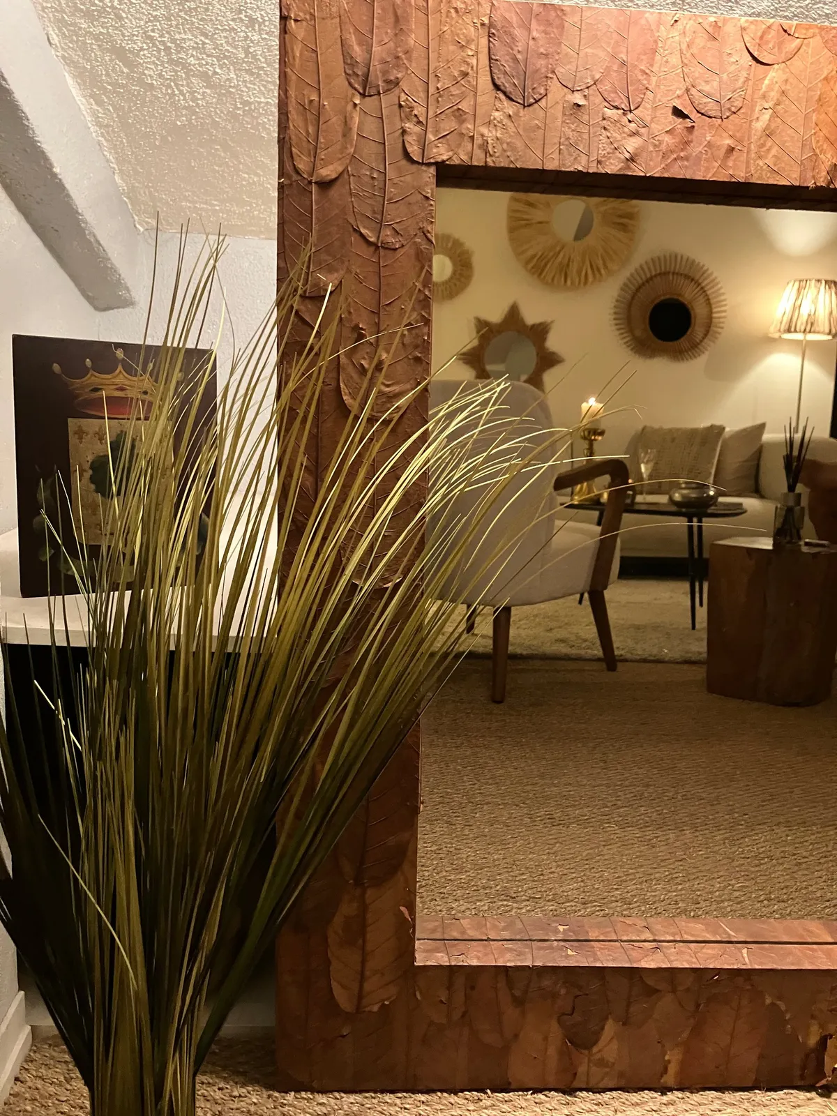 Grand miroir encadré de bois sculpté et herbes hautes, reflet du salon