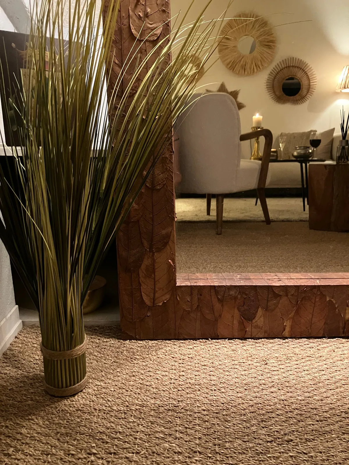 Reflet du salon et de ses miroirs soleil dans un grand miroir en bois