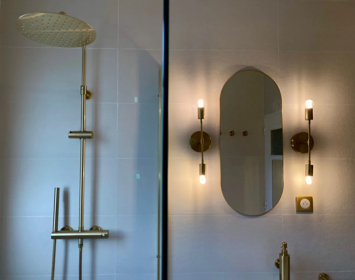 Colonne de douche en laiton brossé et miroir ovale éclairé par deux appliques