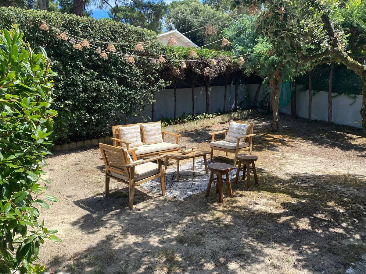 Coin salon ombragé au fond du jardin, guirlande suspendue entre les arbres