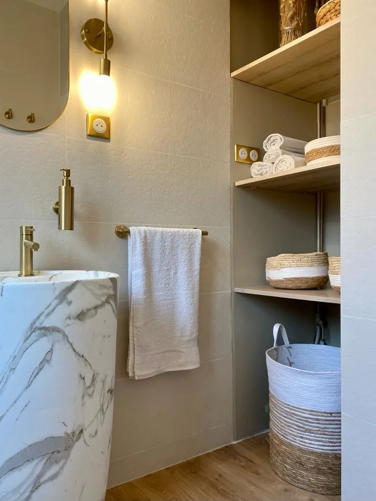 Vasque effet marbre, porte-serviettes en laiton et étagères de bois clair