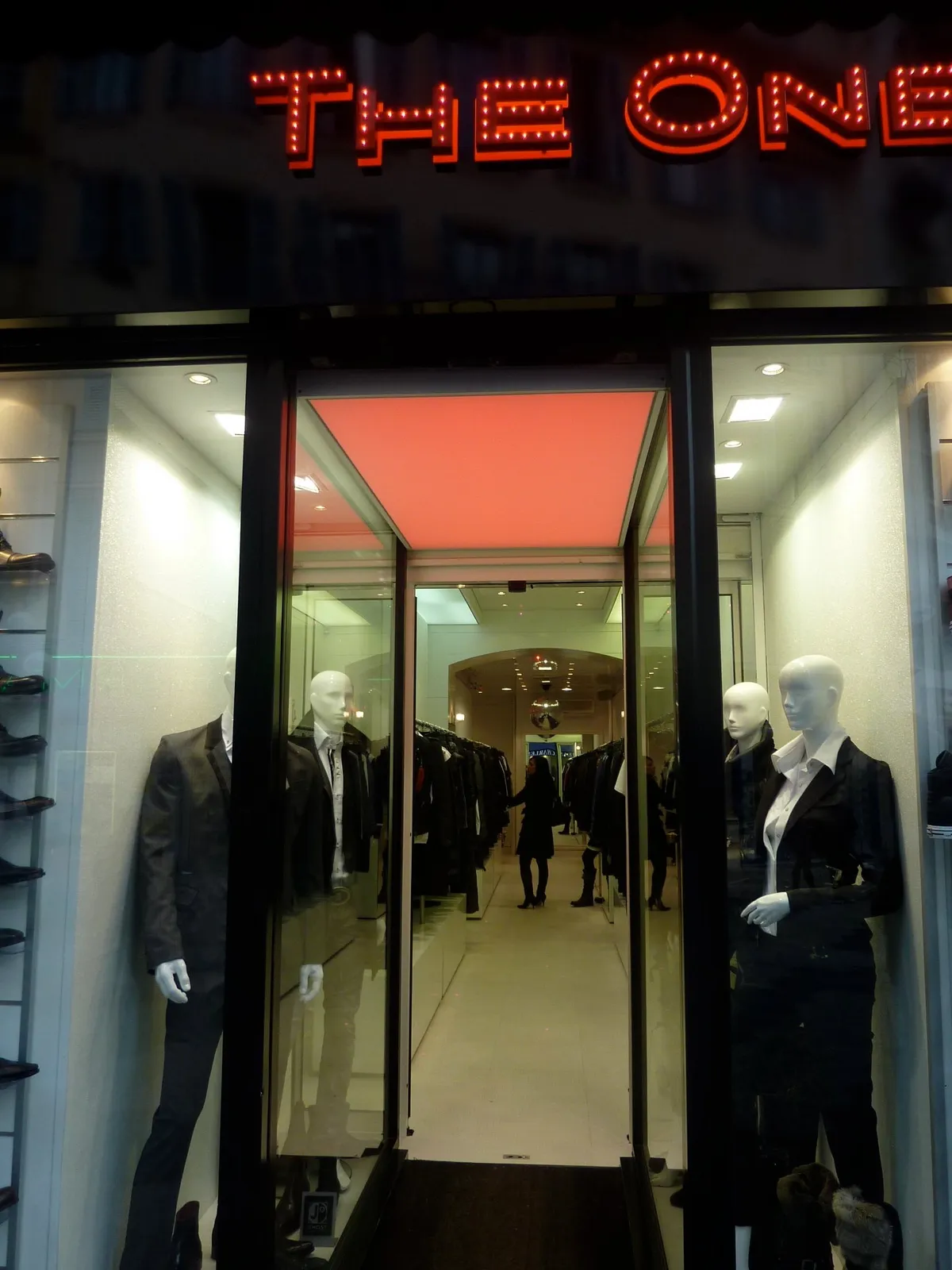 Vitrine de la boutique le soir, enseigne lumineuse et mannequins