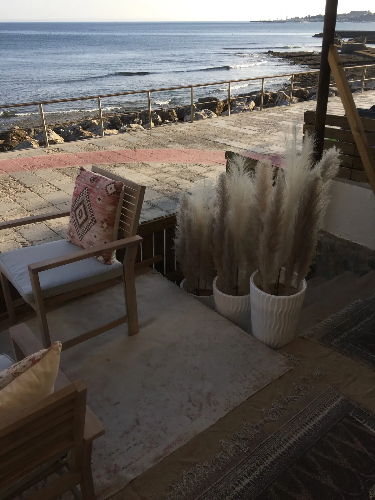 Fauteuils en bois et herbes de la pampa face à l'océan